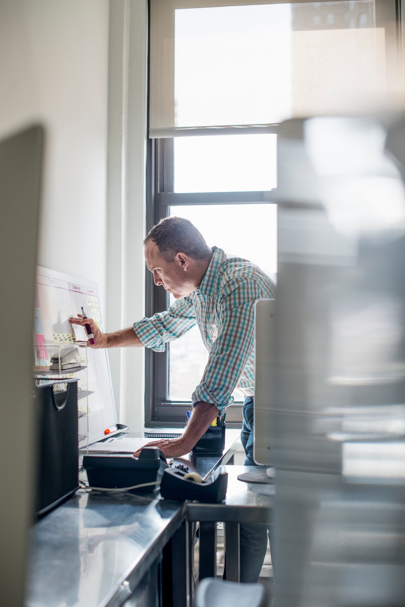 Office life. A man standing up working and making notes on a wall chart. Project management.
